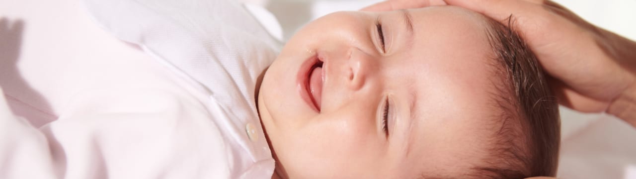 Bébé souriant se faisant caresser la tête